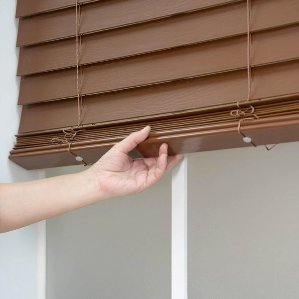 Hand adjusting bottom rail of wooden blinds
